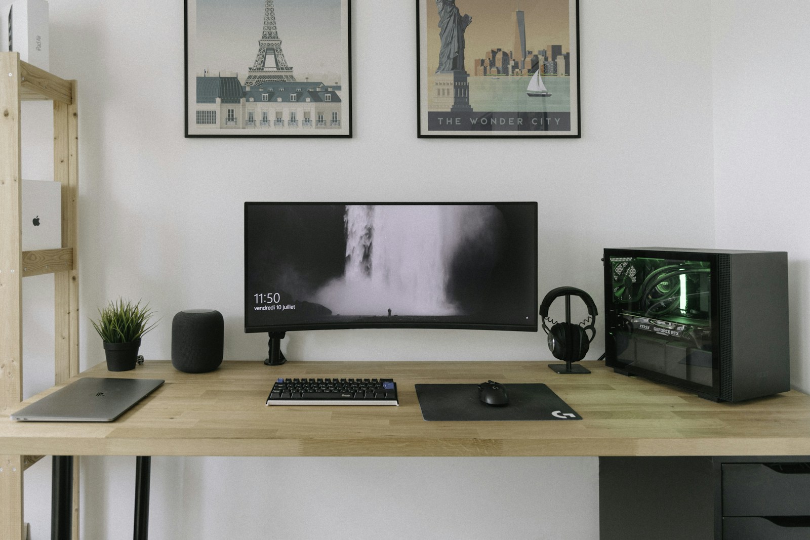 Minimal home office with an ultrawide monitor, keyboard, computer tower, and wooden desk.